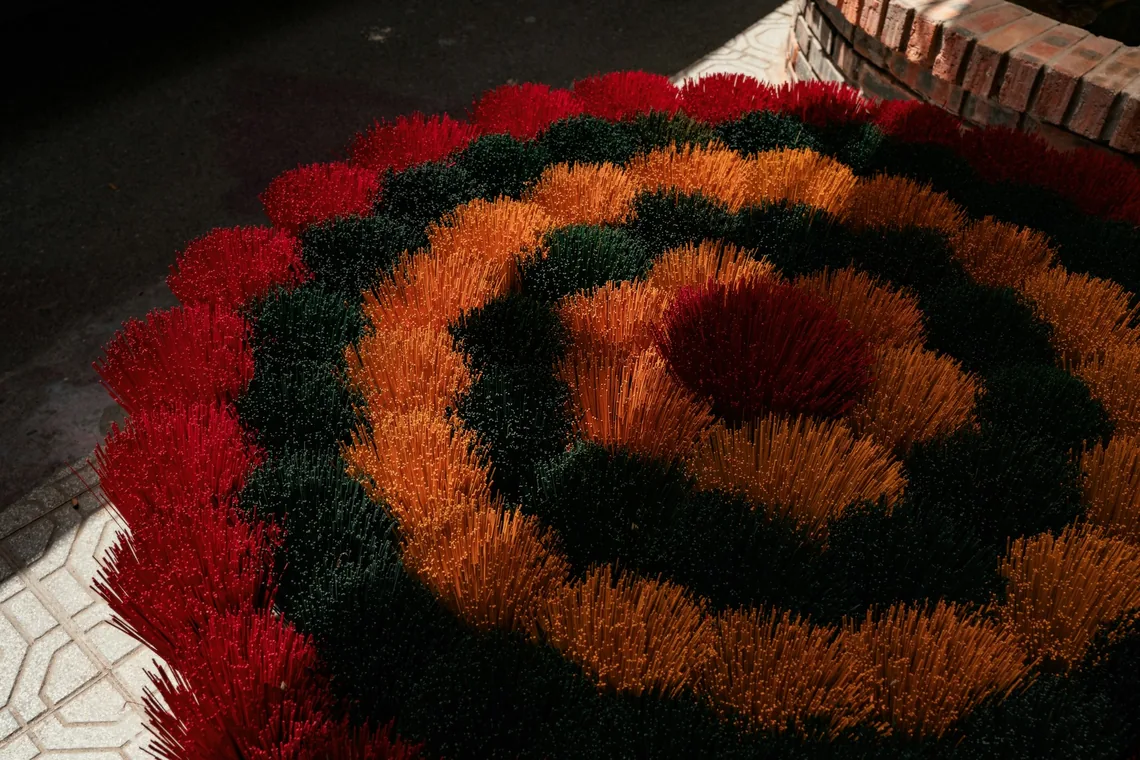 Superficie de una alfombra tufteada con pelo cortado en tonos rojos, naranjas y verdes